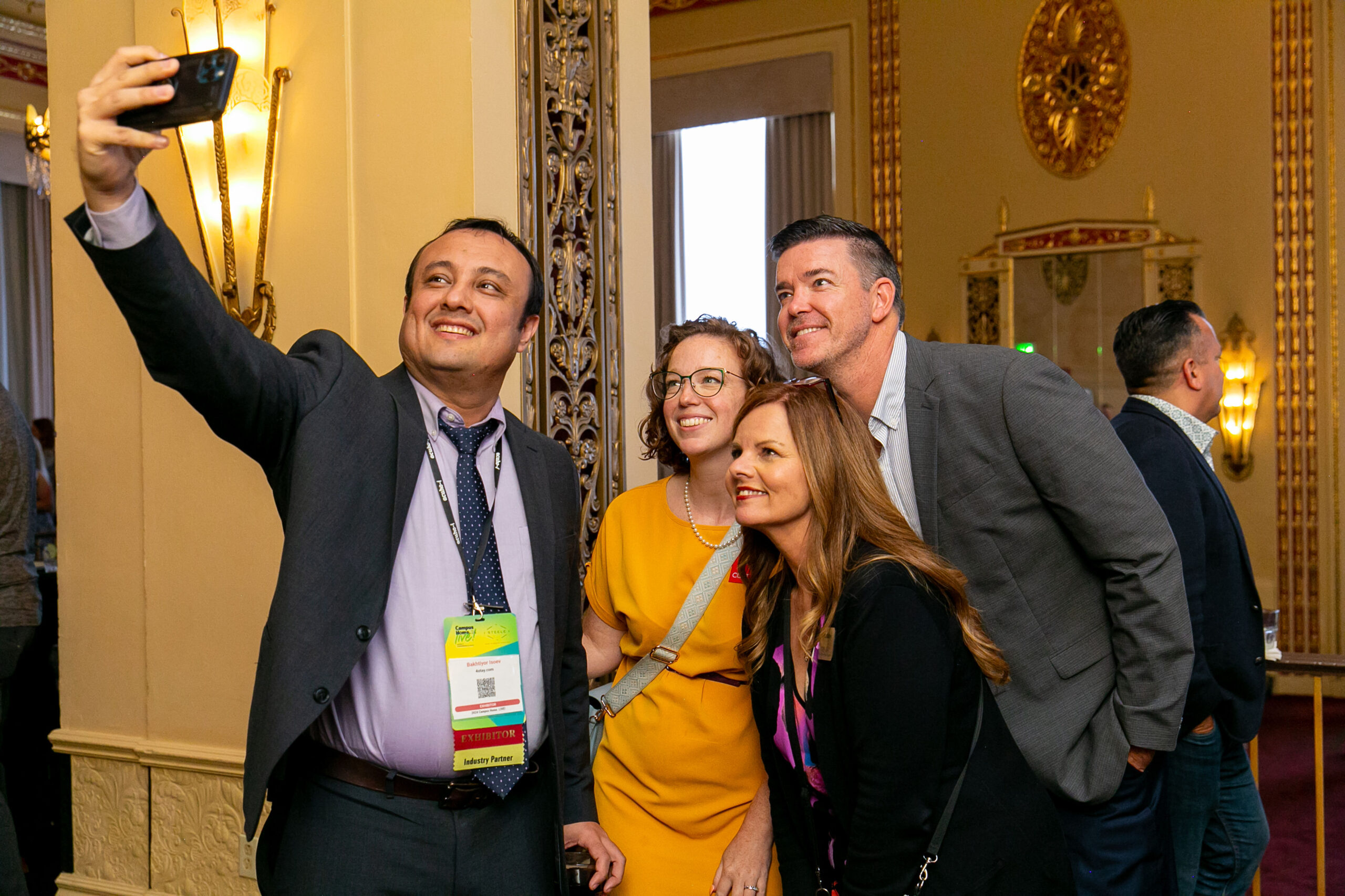 Group of four delegates taking a selfie with a phone.